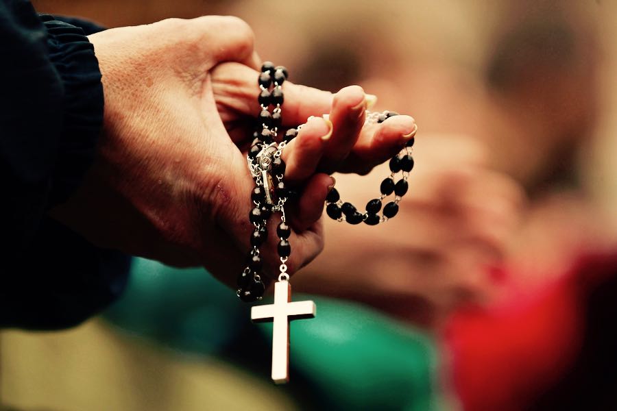 il rosario tra le mani di un prete cattolico