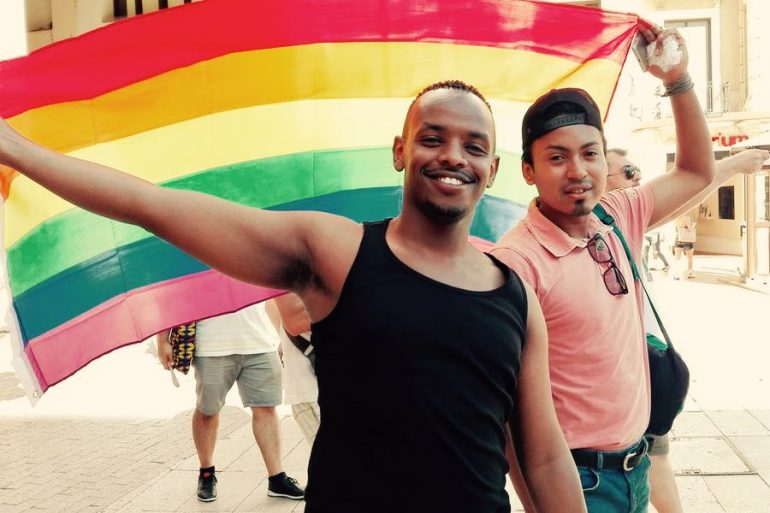 migranti lgbt con bandiera rainbow