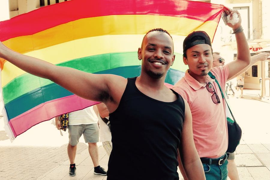 migranti lgbt con bandiera rainbow